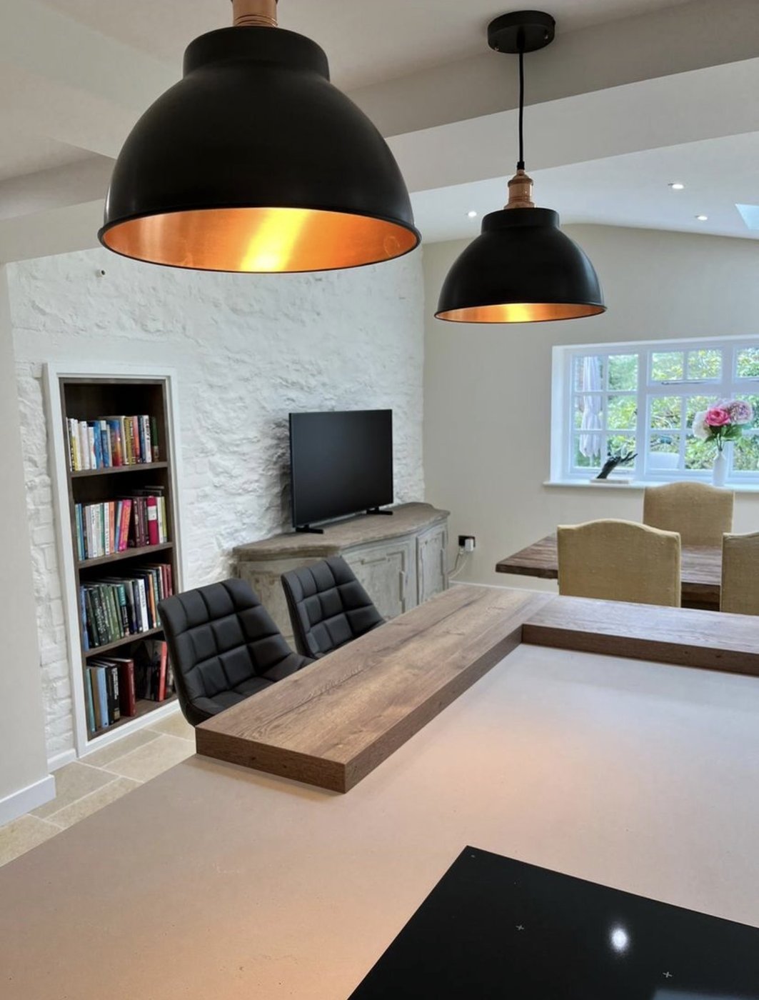 Whitewashed Cotswold stone wall with black industrial pendants and copper interiors