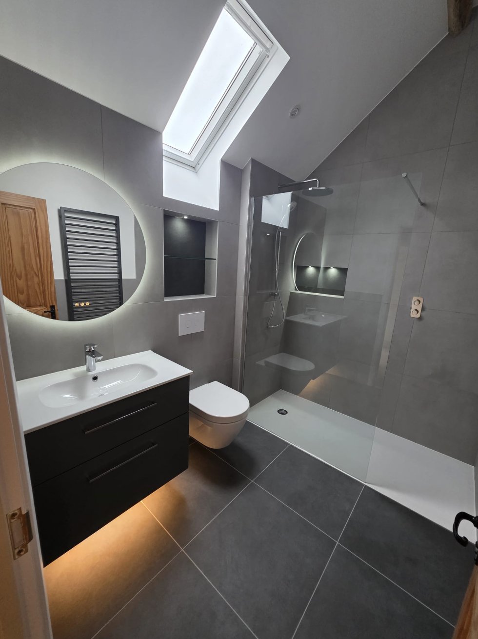 Modern grey bathroom with backlit circular mirror and walk-in shower